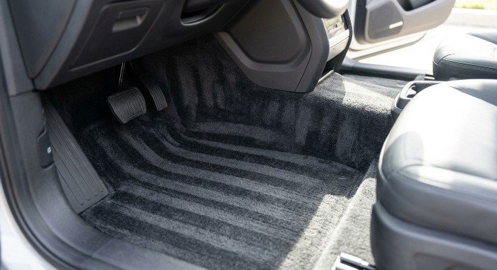 A satisfyingly clean and freshly vacuumed dark gray car carpet showing perfect detailing lines inside a vehicle cabin