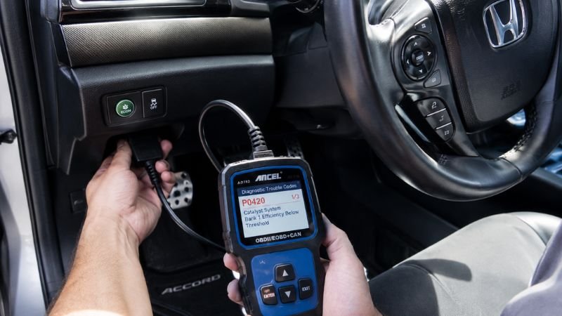 OBD-II diagnostic scanner plugged into Honda dashboard port to clear VSA light codes