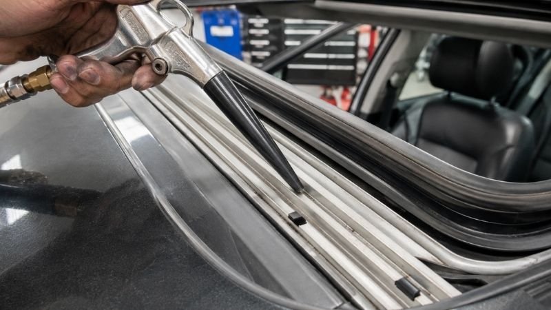 Mechanic cleaning drainage channels and rubber seals on a panoramic sunroof