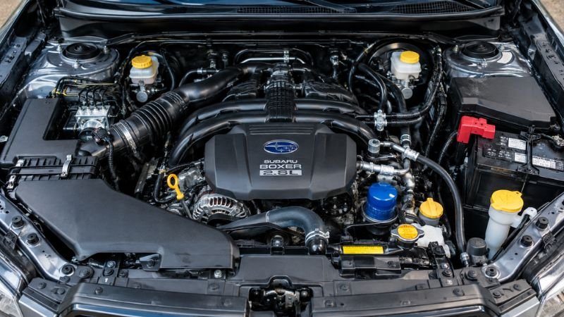 Open engine bay of a Subaru Forester showing the 2.5L FB25 boxer engine layout and oil dipstick for mechanical inspection